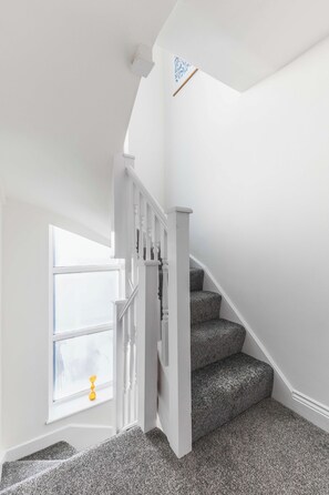 A staircase with a white railing and carpeted steps leading to a landing. - Modern Garden House Stratford FREE Street Parking (Greater London)