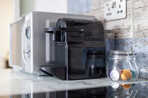 A Nespresso coffee machine on a kitchen counter with a jar of coffee capsules. - Cozy Studio, Close to Arsenal Finsbury Park (Greater London)
