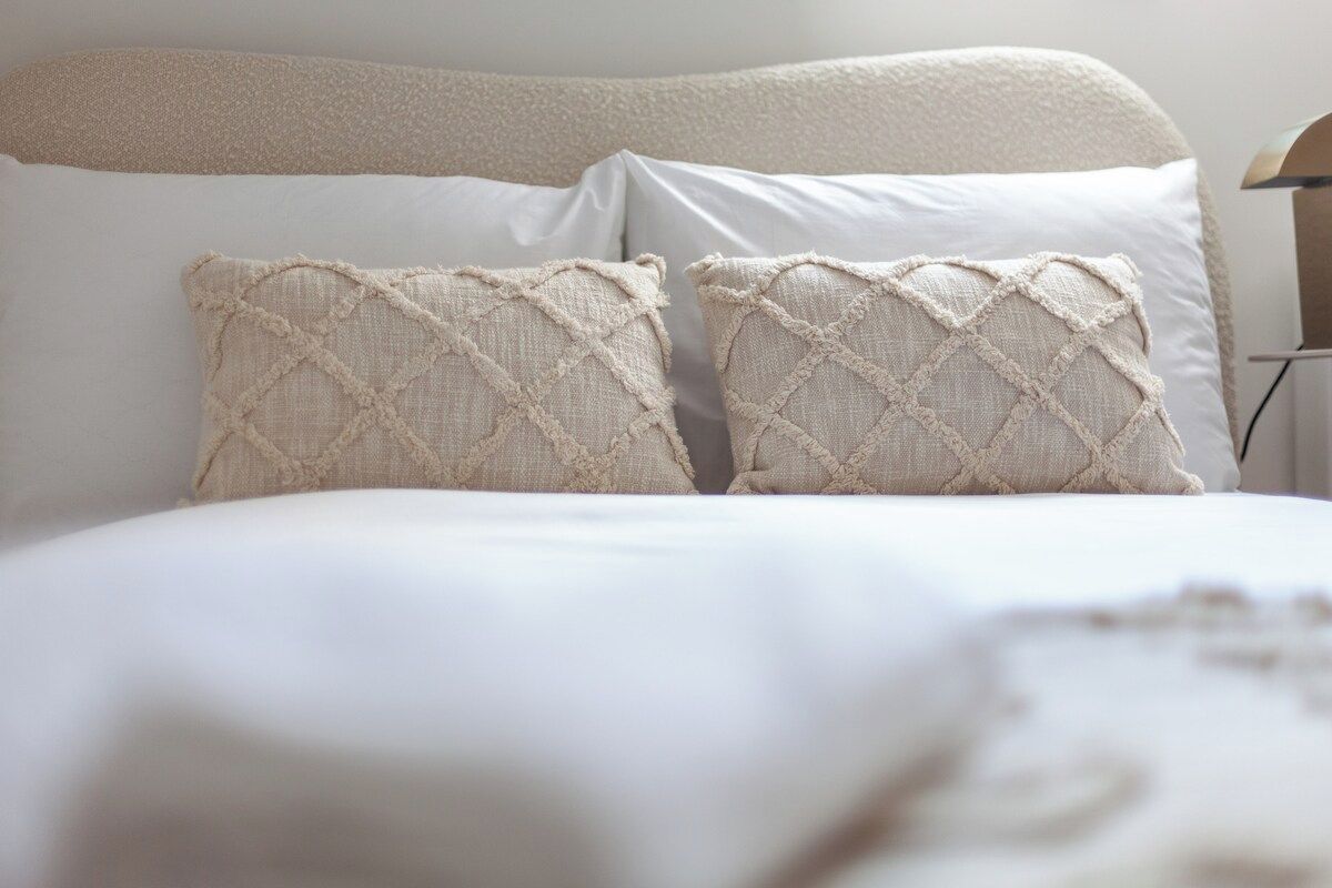 A bed with a headboard, two pillows, and a blanket.