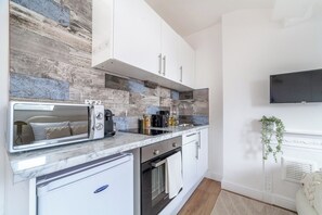 A compact kitchen with a built-in oven, a microwave, and a coffee maker. - Cozy Studio, Close to Arsenal Finsbury Park (Greater London)