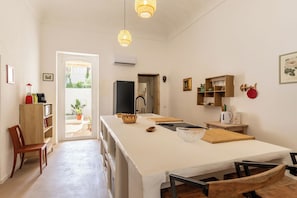 Eine Küche mit einer zentralen Kochinsel, Holzschränken, einem Kühlschrank und einem Essbereich mit Stühlen.