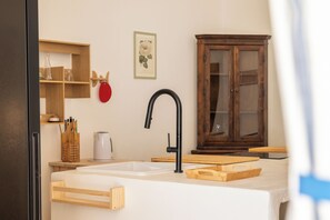 Eine Küche mit weißem Spülbecken, einem schwarzen Wasserhahn, Holzschränken und einer Holzarbeitsplatte.