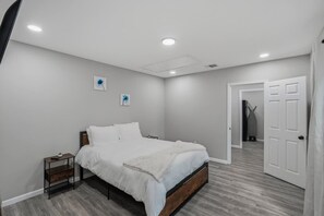 Ein Schlafzimmer mit Bett, Nachttisch, Tür und einem Flur.