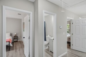 A hallway with a bed, bedside table, and a bathroom with a toilet and sink. - Cozy 3BR Duplex Laundry Min to Downtown (San Antonio)