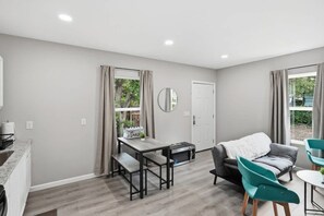 A modern living room with a dining table, a sofa, and a small round table with chairs. - Cozy 3BR Duplex Laundry Min to Downtown (San Antonio)
