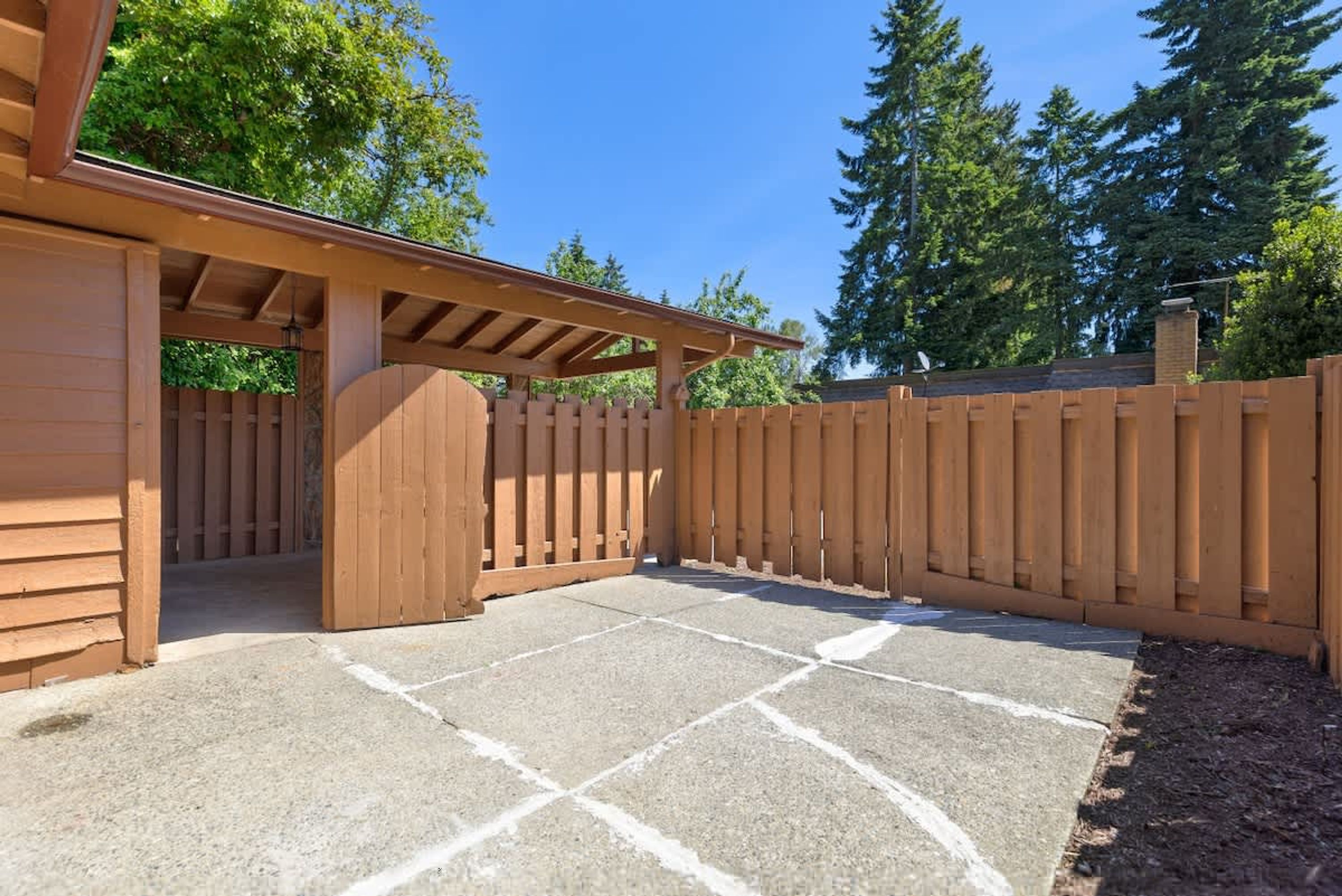 A covered patio area with a wooden fence and a pergola structure.