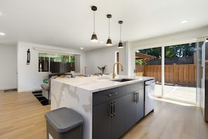 Una cocina moderna con una isla central, iluminación colgante y vistas al patio trasero.