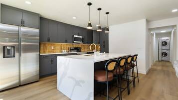 A modern kitchen with a central island, stainless steel appliances, and a built-in microwave.