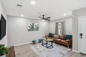 Ein Wohnzimmer mit braunem Ledersofa, einem Couchtisch und einem Deckenventilator.