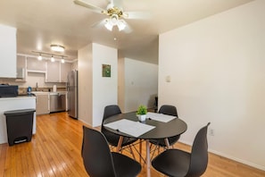 A modern kitchen with white cabinets, a stainless steel refrigerator, and a ceiling fan. - Family-friendly 2BR Home in Lynnwood w Parking (Lynnwood)