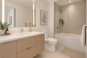 Un baño moderno con lavamanos, inodoro y zona de ducha con mampara de cristal.