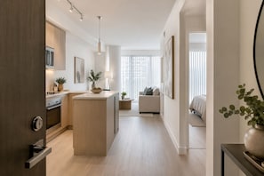 Cocina moderna con una isla central, comedor con sofá y dormitorio con cama.