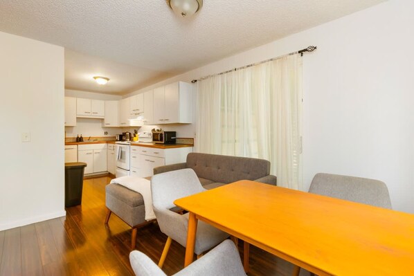 A compact living space with a kitchenette, a dining area with a table and chairs, and a sofa. - Cozy 2BR Home in Lynnwood w Backyard (Lynnwood)
