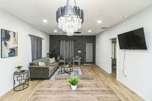 Ein modernes Wohnzimmer mit einem grauen Sofa, einem Couchtisch und einer Kristallleuchtre.