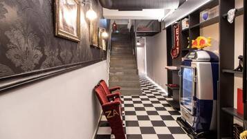 A hallway with a checkered floor, a red chair with 'ZA' on it, a vending machine, and a staircase in the background.