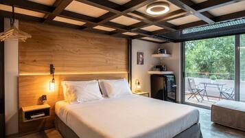 A modern bedroom with a large bed, bedside tables, a nightstand, a desk, and a balcony with outdoor seating.