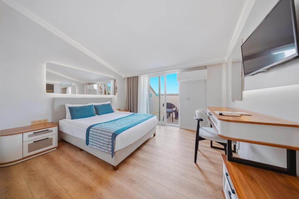 Une chambre à coucher comprenant un lit, une table de chevet, un téléviseur et un bureau avec une chaise.