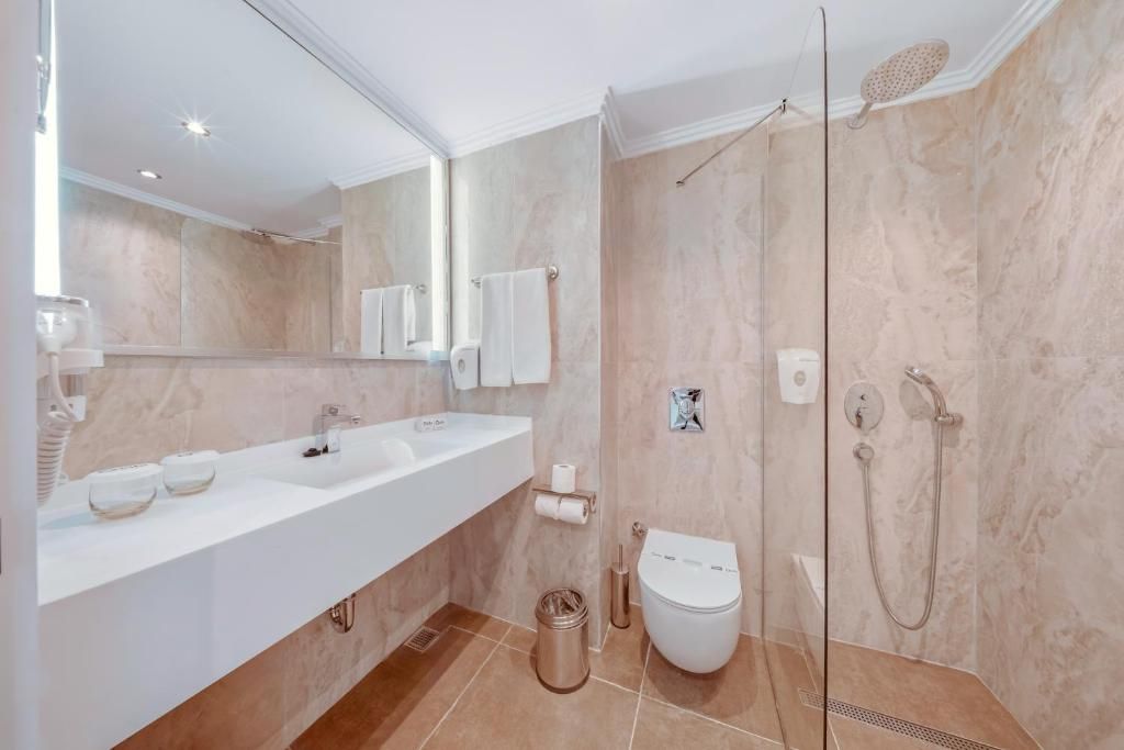 Une salle de bain moderne avec un meuble-lavabo à deux vasques, des toilettes, une cabine de douche et un grand miroir.