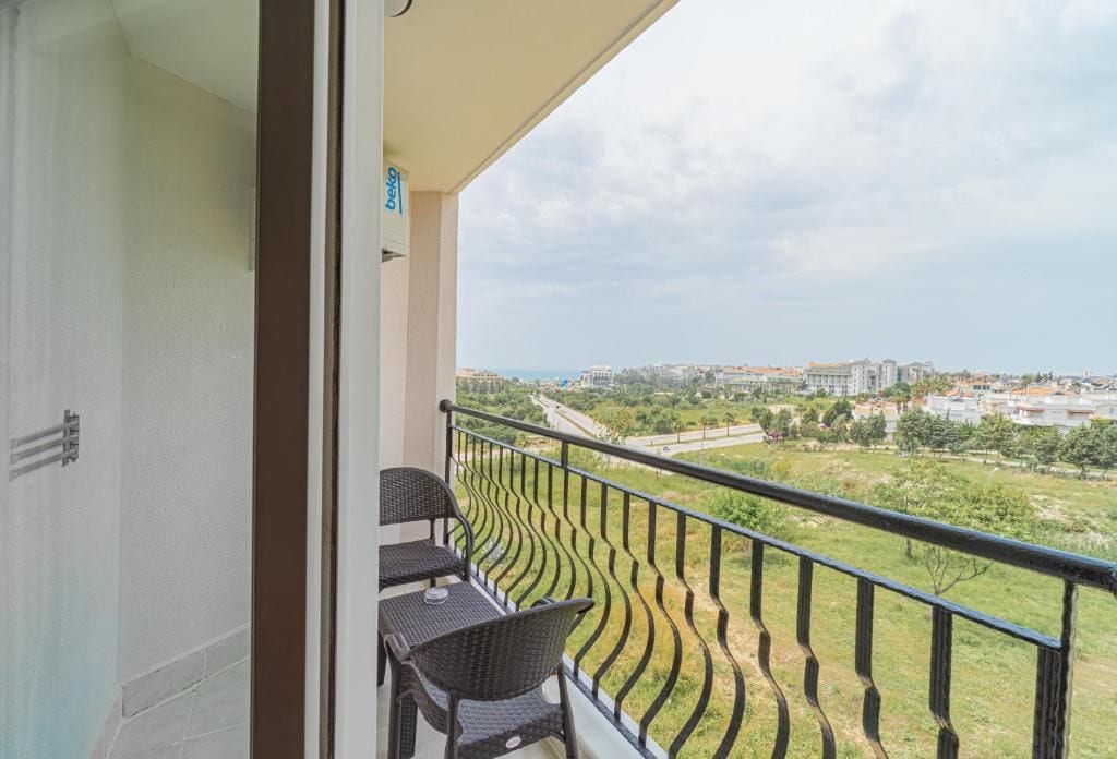 A balcony with a view of a cityscape and greenery.