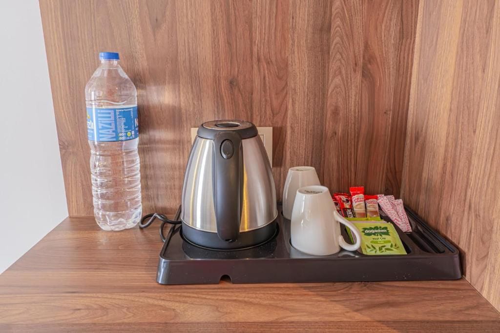 Eine Kaffeemaschine, eine Wasserflasche und ein Tablett mit Kaffeetassen und Hundefutter auf einer Holztischplatte.