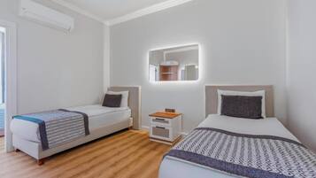 Een moderne hotelkamer met twee enkele bedden, een klein nachtkastje en een spiegel erboven.