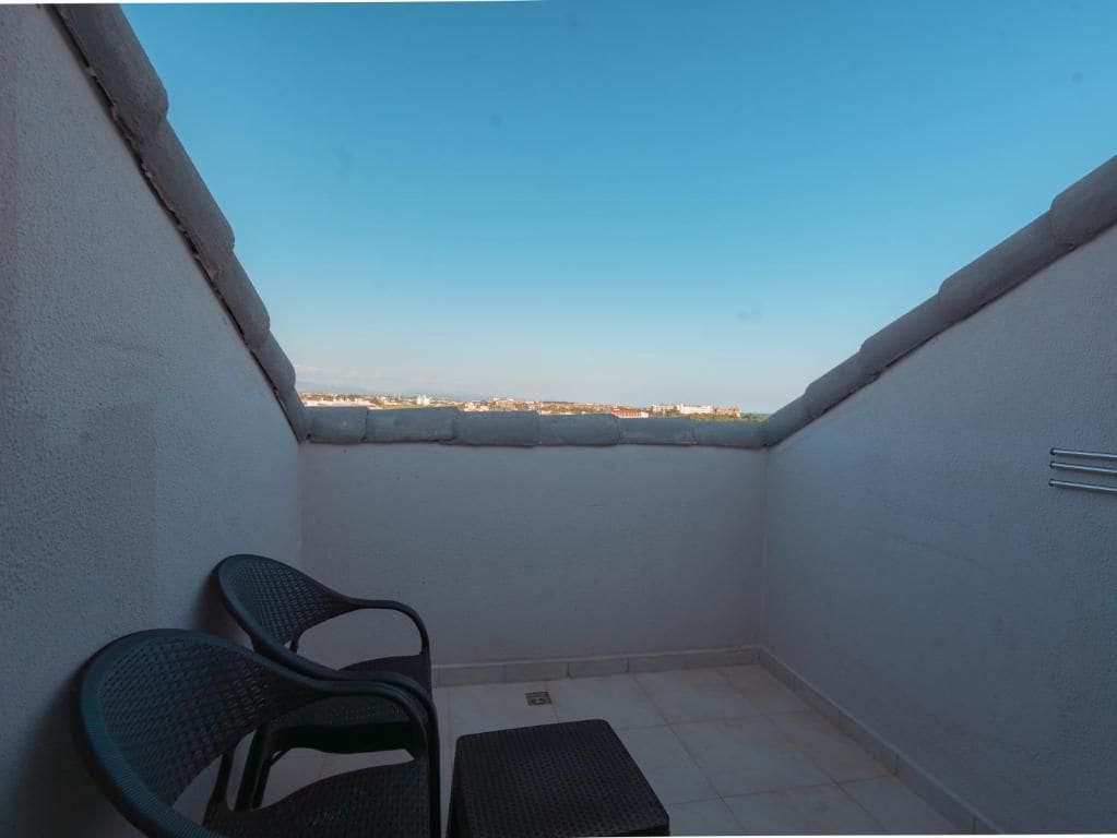 A small balcony with a view of a distant cityscape, a chair, and a small table.