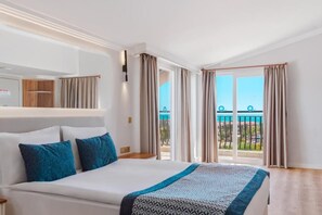 Habitación de hotel con cama, mesita de noche, espejo y vista al exterior.