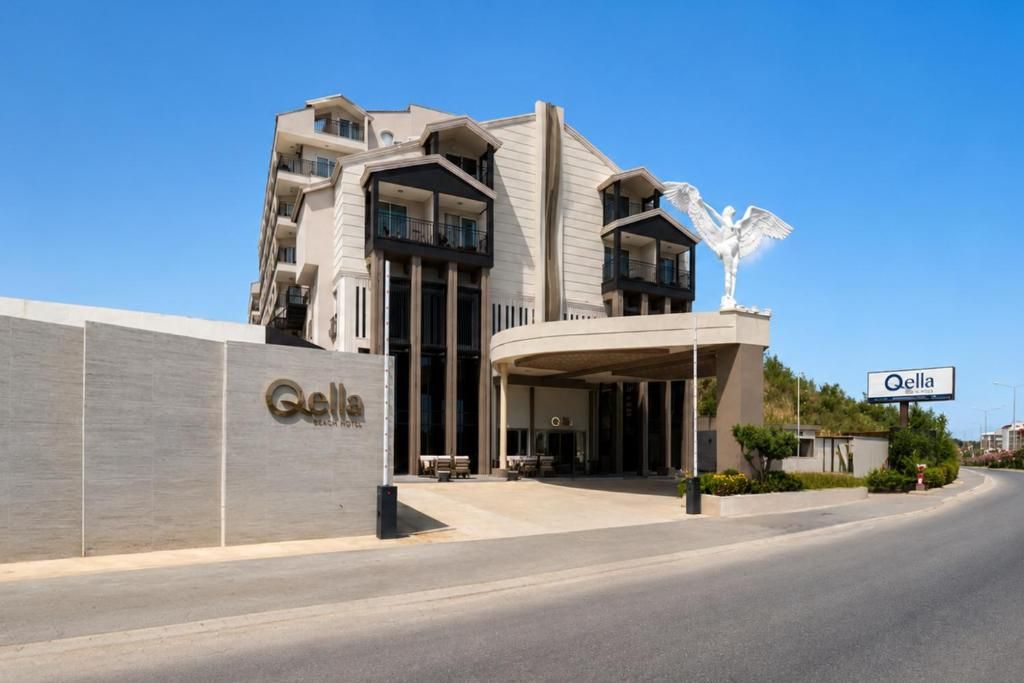 Un hotel moderno con una entrada curva, una estatua destacada y un cielo despejado.