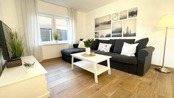 A living room with a sofa, a coffee table, a TV stand, and a lamp.