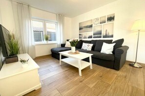 Ein Wohnzimmer mit Sofa, Couchtisch, TV-Schrank und Lampe.