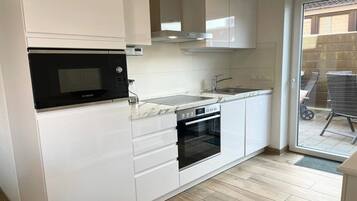 A compact kitchen with a Bosch microwave, a built-in oven, and a sink.