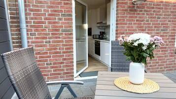 An outdoor patio with a table, a chair, and a potted plant.
