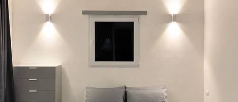 A bedroom with a bed, a dresser, and two wall-mounted lights.