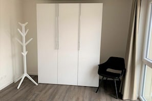 Een kamer met een kledingkast, kapstok en een stoel.