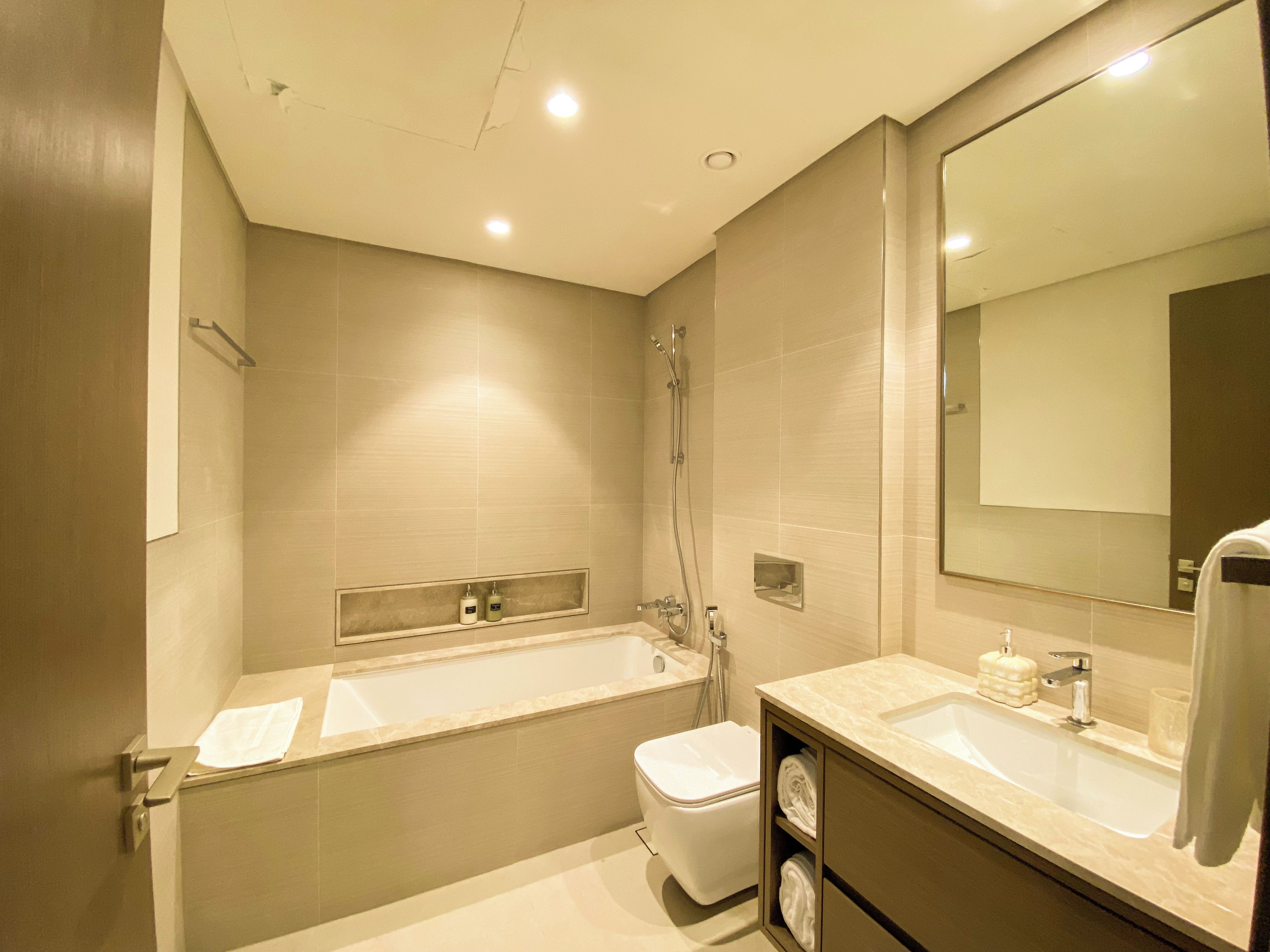 A modern bathroom with a bathtub, a toilet, a sink, and a mirror.