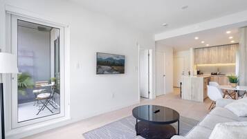 A modern living room with a glass door leading to a balcony, a round coffee table, and a sofa.