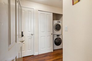 A laundry room with two stacked washing machines and a door leading to another room. - Cozy Work-ready 1BR Condo Near Downtown (Bellevue)