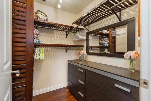 A walk-in closet with wooden shelves, a vanity with a mirror, and a dresser. - Cozy Work-ready 1BR Condo Near Downtown (Bellevue)
