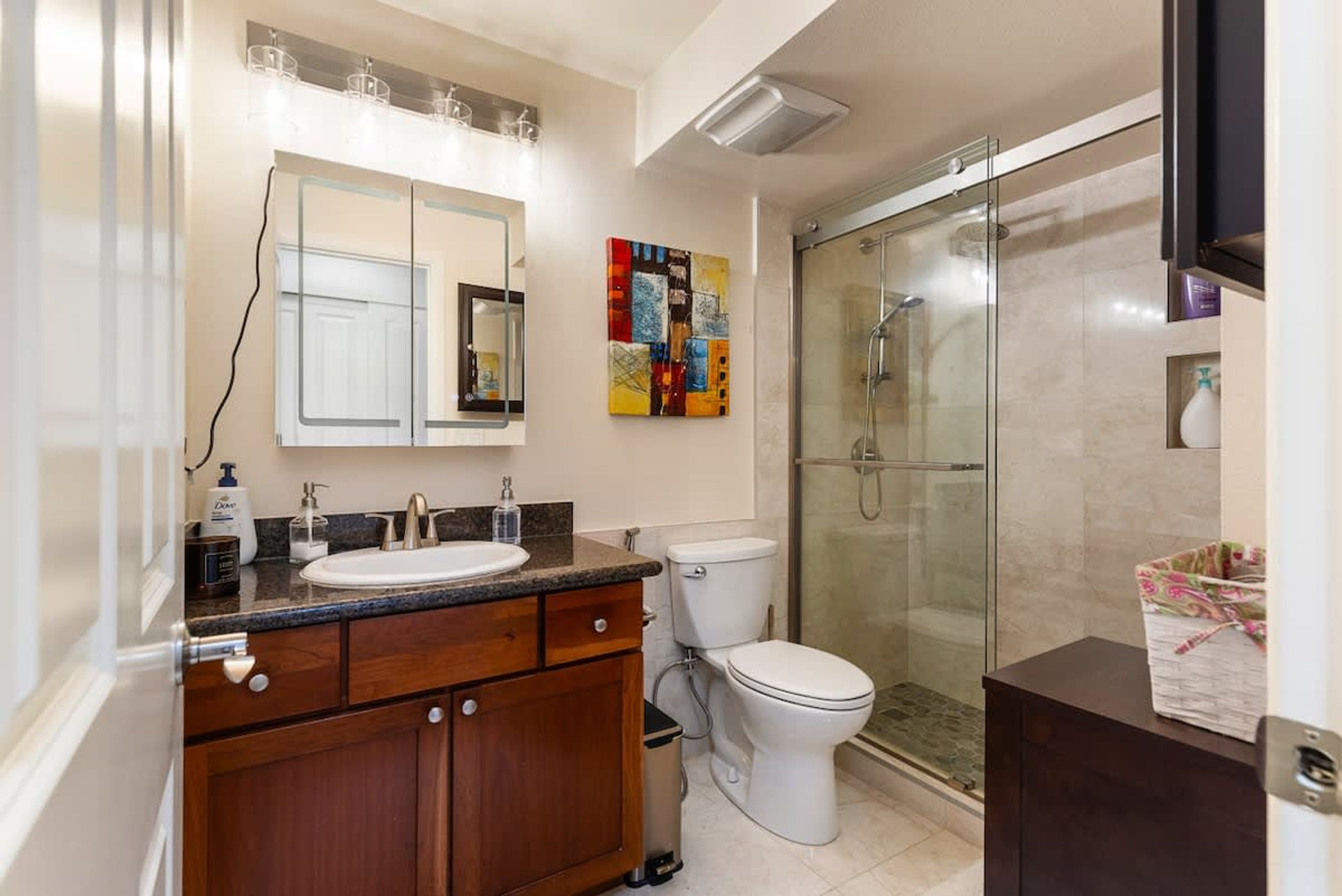 Une salle de bain moderne équipée d’un lavabo, d’un miroir, de toilettes et d’une douche.