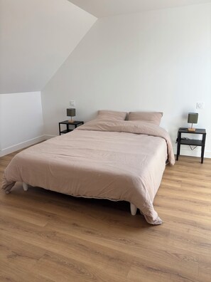 A bedroom with a large bed, two nightstands, and a sloped ceiling. - Fully renovated rural vacation rental (Pleyben)