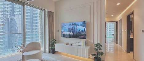 A modern living room with a large flat-screen TV, a sofa, a coffee table, and a potted plant.