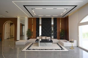A modern lobby with a seating area, a large window, and a decorative wall. - Auja Residence Katemeya Dunes (New Cairo)