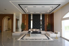A modern lobby with a seating area, a large mirror, and a decorative wall. - Auja Residence Katemeya Dunes (New Cairo)