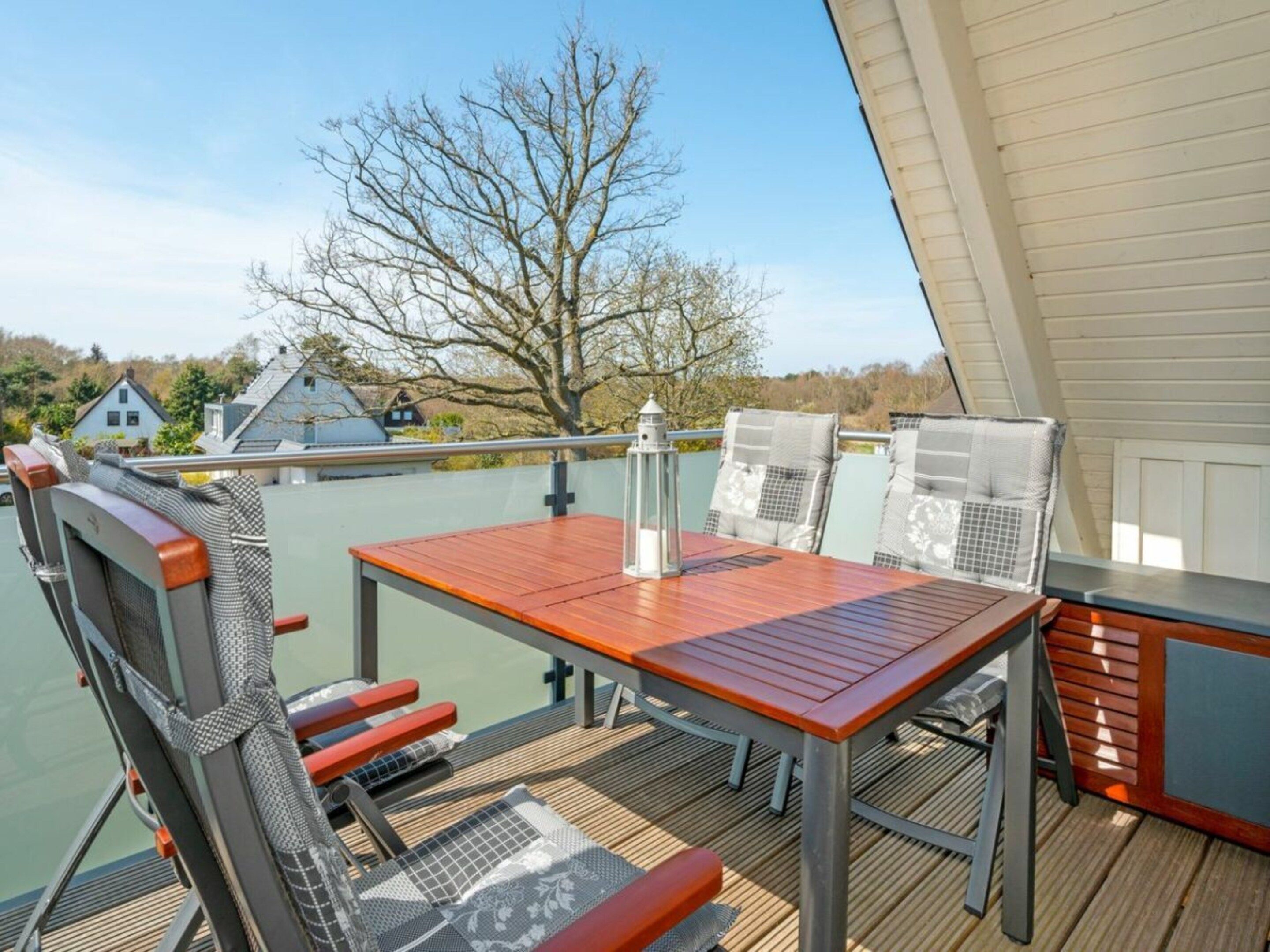 A deck with a table and chairs, overlooking a body of water and houses.