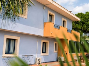 Ein zweistöckiges Gebäude mit Balkon, Fenstern und Gartenmöbeln.