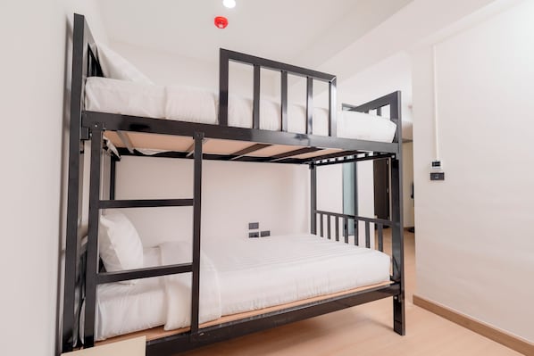 A bunk bed with a headboard, a bedside table, and a wall-mounted light fixture. - Canvas Hotel Pattaya (Pattaya)
