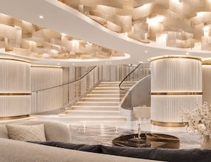 A modern interior with a curved staircase, a seating area with a coffee table, and a decorative wall with textured panels. - Canvas Hotel Pattaya (Pattaya)