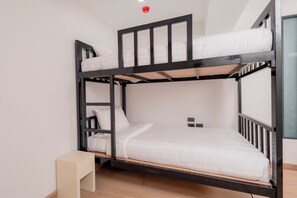 A bunk bed with a wooden frame, white bedding, and a small bedside table. - Canvas Hotel Pattaya (Pattaya)