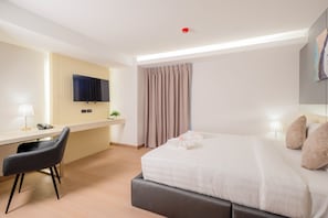 A hotel room with a bed, a desk with a chair, a television, and a window with curtains. - Canvas Hotel Pattaya (Pattaya)
