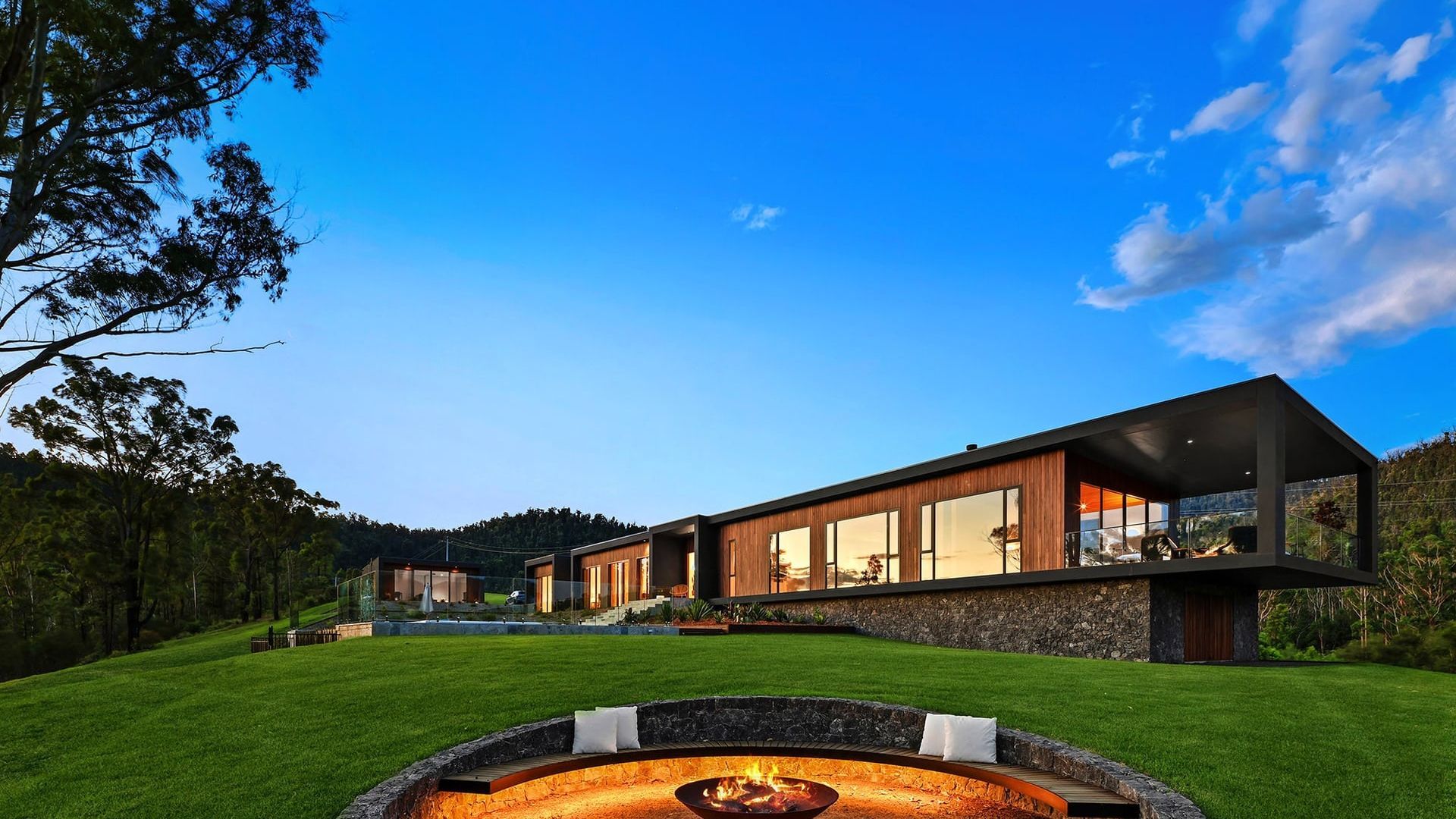 Una casa moderna con un brasero en el jardín delantero.